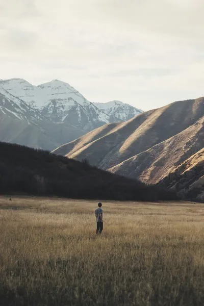 Person standing on open field near mountain — Photo by Devin Justesen on Unsplash