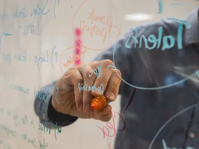 Person writing diagrams on glass whiteboard - Photo by Kvalifik on Unsplash