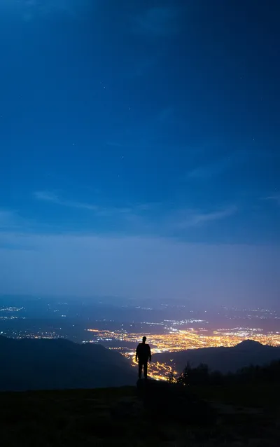 Solitary figure on mountain overlooking city lights - Photo by Theodor Vasile on Unsplash