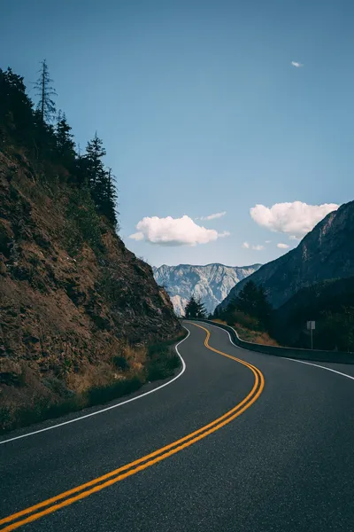 An empty road stretching toward mountains — Photo by Pietro De Grandi on Unsplash