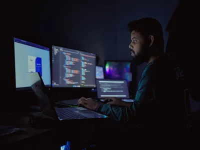 Software developer working late at night with multiple screens — Photo by Abu Saeid on Unsplash