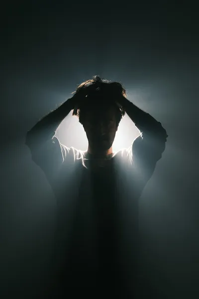 Photo by Cemrecan Yurtman on Unsplash A man overcome by stress and anxiety in the darkness, representing the moment of crisis that begins the journey