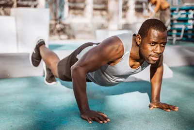 Photo by Fortune Vieyra on Unsplash A man working out doing push-ups outdoors, representing the elimination of dependencies and simplicity of training