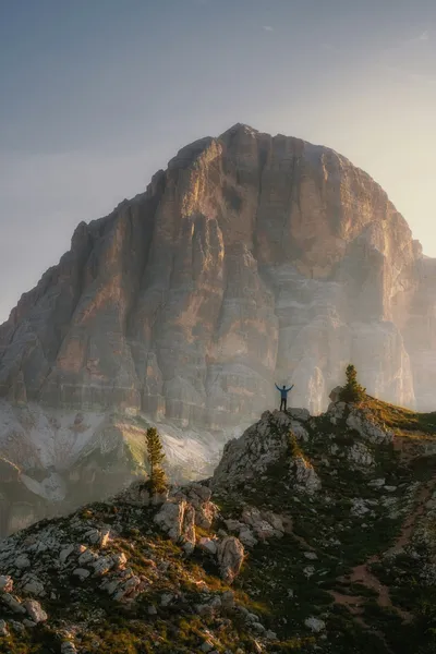 Hiker celebrates on mountain peak at sunrise, finding clarity and solitude above the chaos. Photo by Marco Grosso on Unsplash