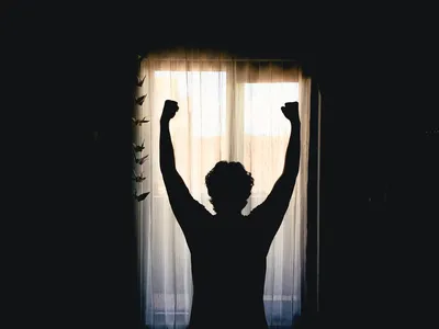 Silhouette of person with arms raised in victory, celebrating the transformative power of early mornings. Photo by Husam El Haq on Unsplash