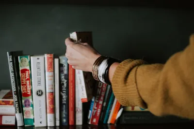Person picking book from shelf — Photo by Christin Hume on Unsplash